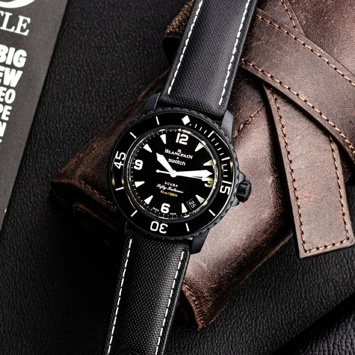 Black wristwatch with leather strap on a textured surface