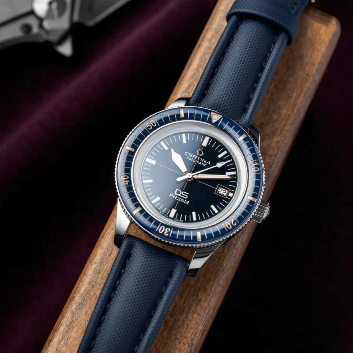 Wristwatch with blue strap and dark face on a wooden surface