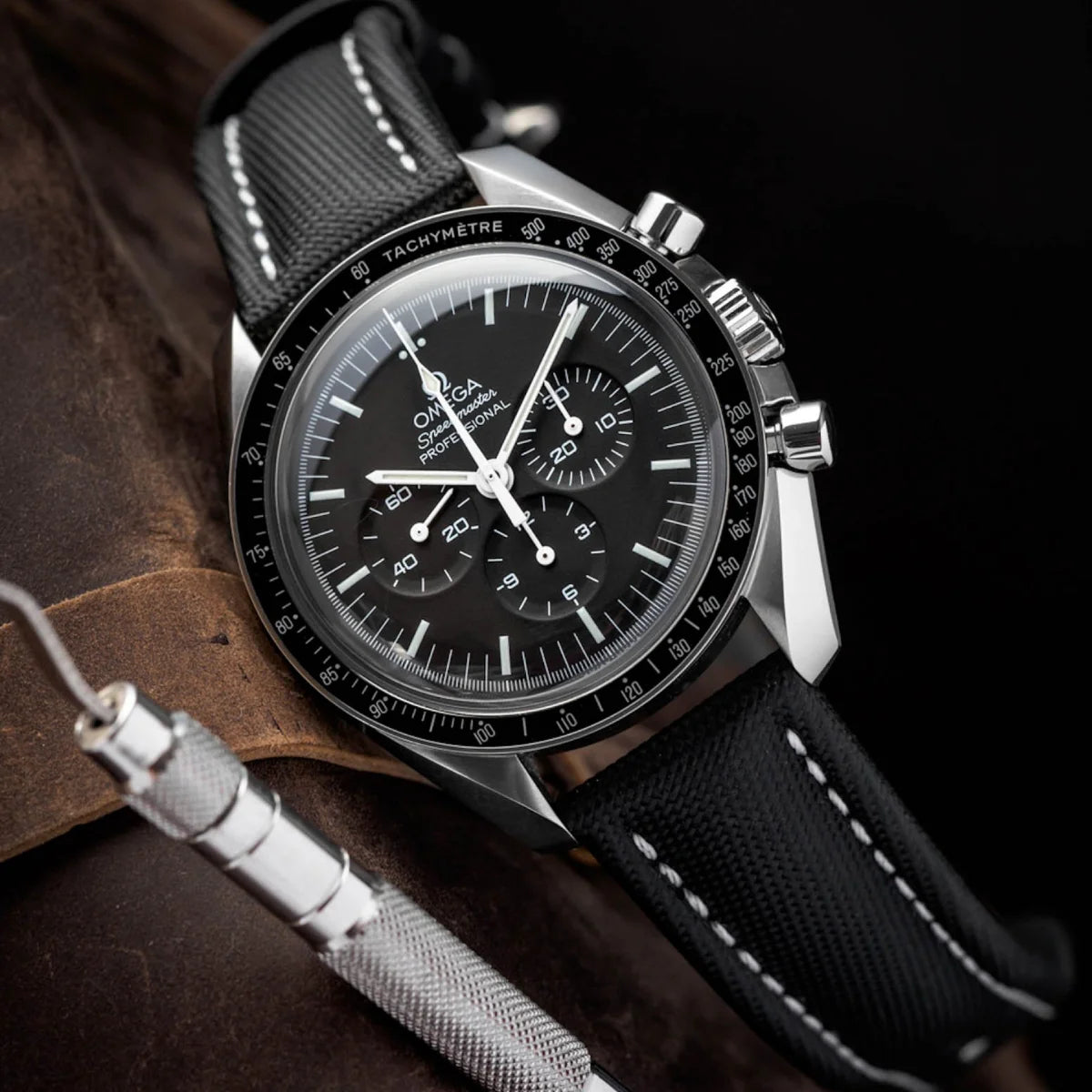 Close-up of a black wristwatch with a detailed face on a dark background