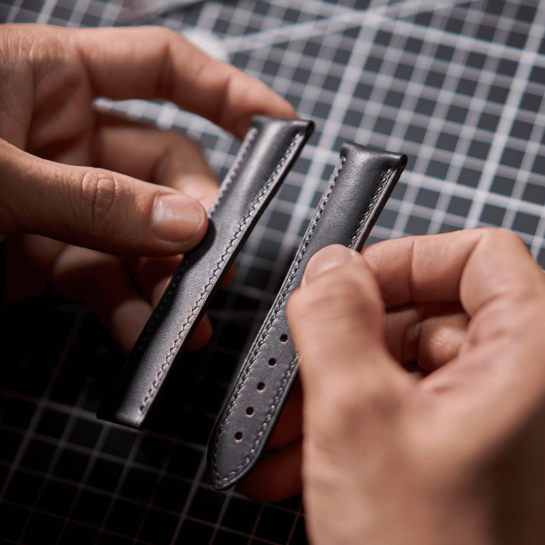 Close-up of hands holding a black leather wallet against a checkered fabric background