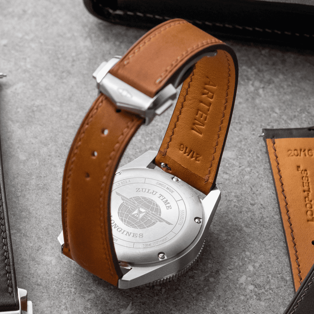 Watch with brown leather strap on a gray surface