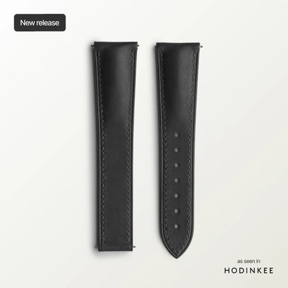 Black leather watch strap on a light gray background with 'HODINKEE' branding.