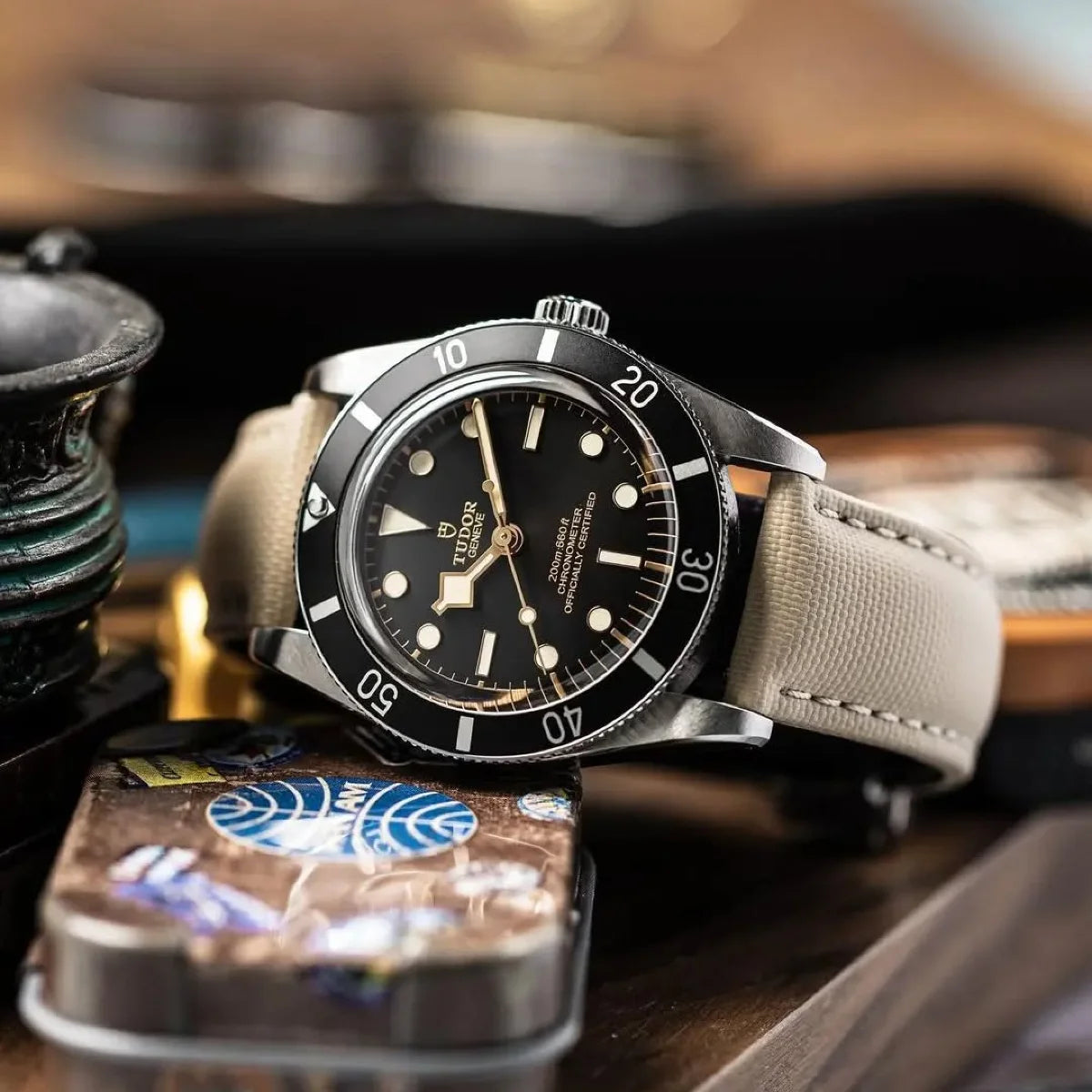 Watch with a black dial and beige strap on a wooden surface