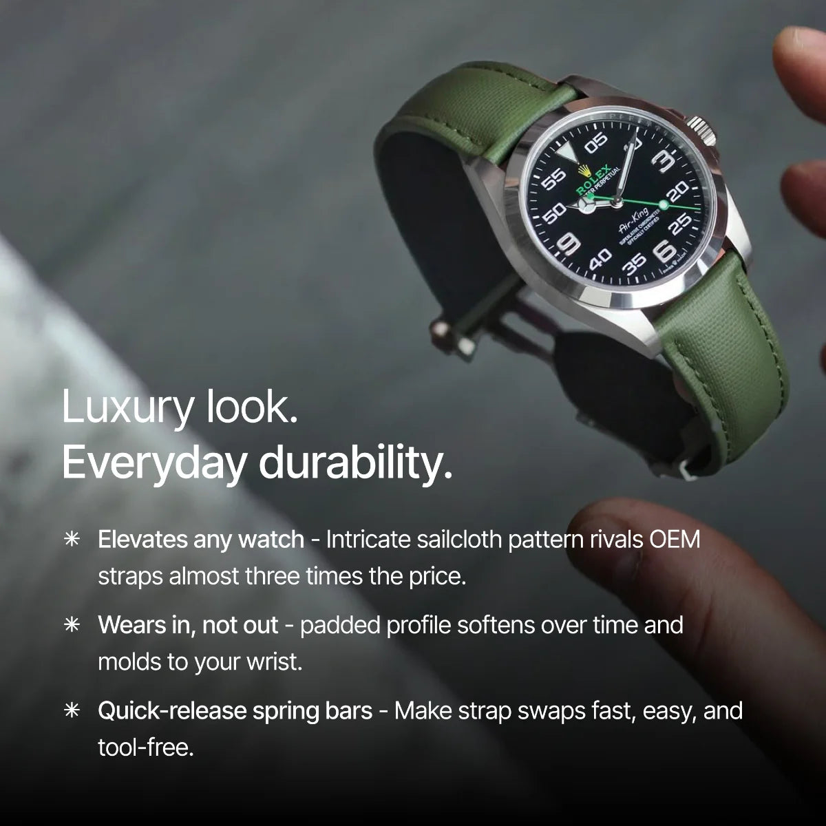 Watch with green strap held by a hand against a blurred background