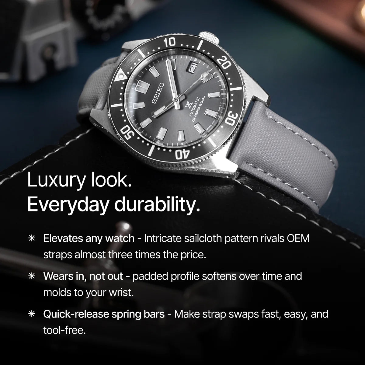 Watch with gray strap and dark face on a dark background, text highlighting features.