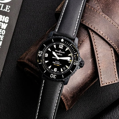Black wristwatch with leather strap on a textured surface