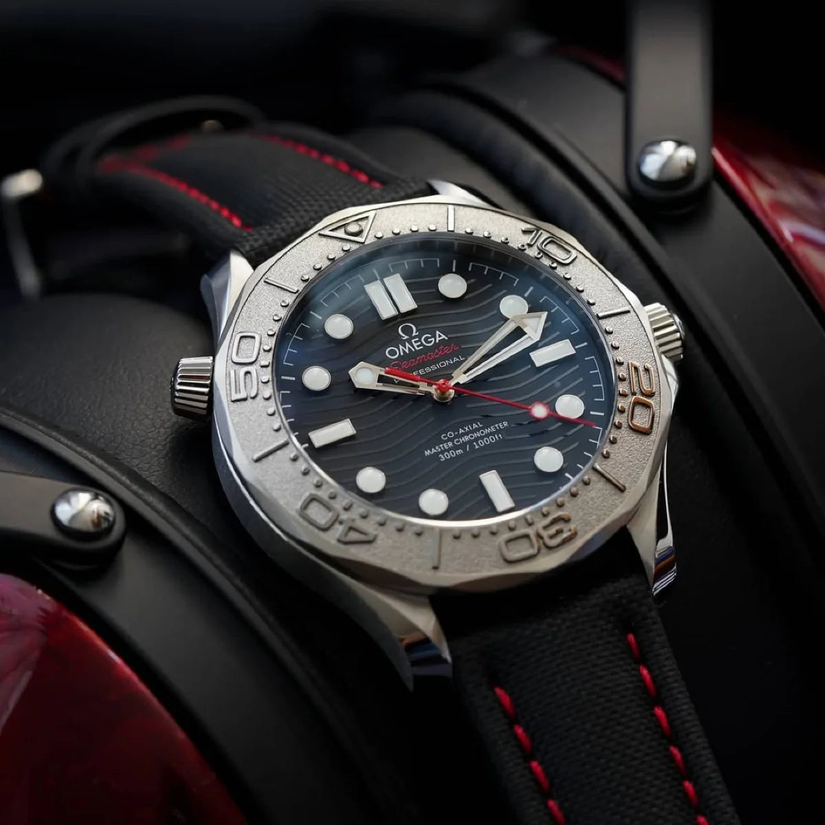 Omega watch with black dial and red accents on a dark background