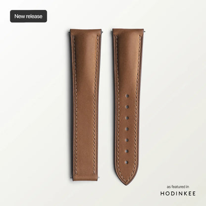 Brown leather watch strap on a light gray background with 'Hodinkee' branding.